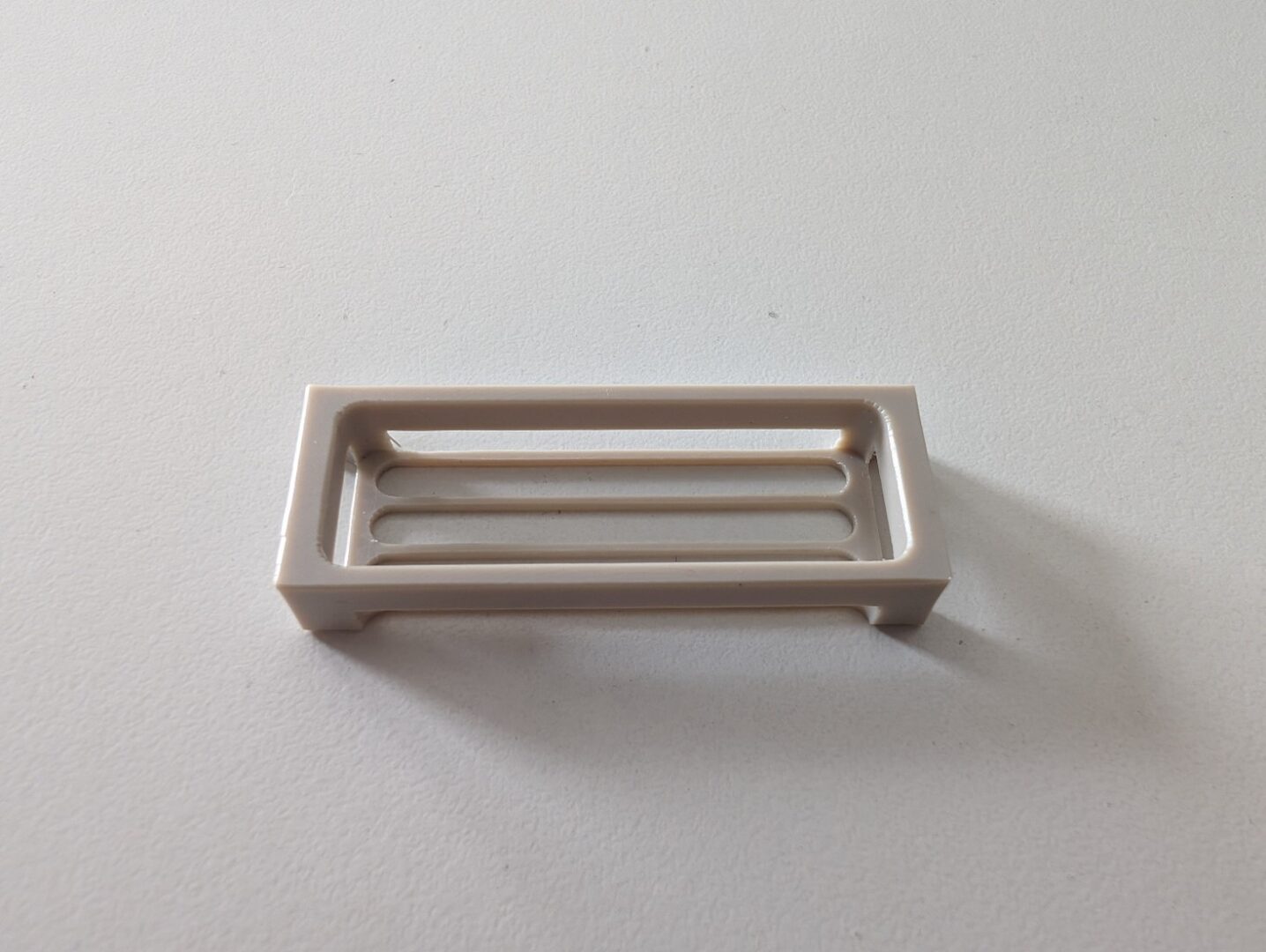 Cestello tecnico in PEEK con struttura rettangolare e fessure longitudinali, progettato per applicazioni medicali.